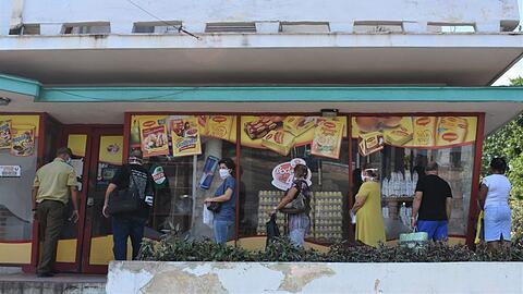 Menschen mit Mundschutz in Havanna vor einem Lebensmittelgeschäft Schlange.