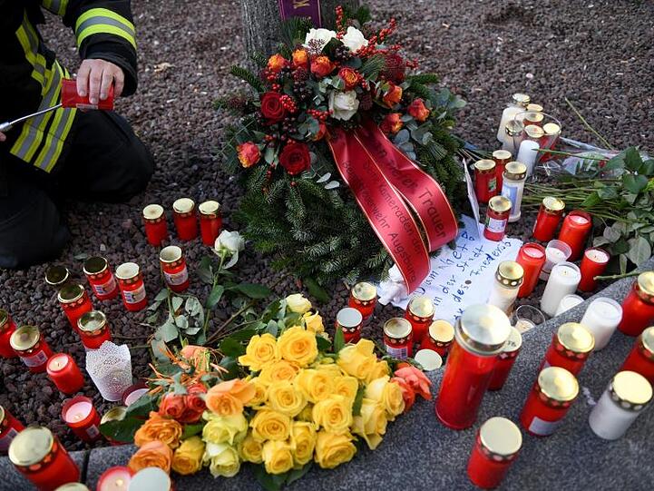 Am Königsplatz zündet ein Feuerwehrmann eine Kerze an. Foto: Stefan Puchner/dpa