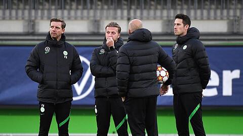 Vor dem Abflug nach Sevilla war Corona wieder ein Thema: Wolfsburgs Trainer Florian Kohfeldt (l) steht mit seinem Team zusammen.