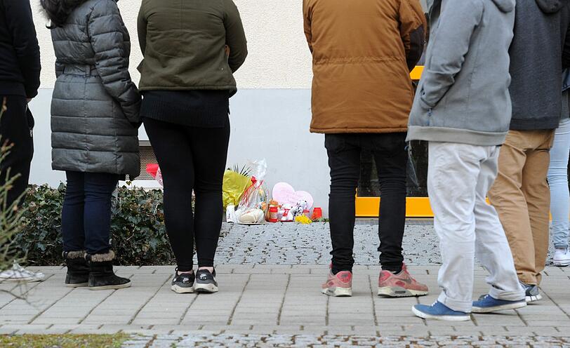 Jugendliche stehen in Unterföhring vor einem Hauseingang an dem Blumen, Kerzen und Stofftiere abgelegt wurden.