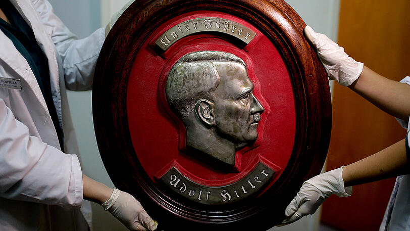 Mitglieder der Bundespolizei halten im Interpol-Hauptquartier in Buenos Aires ein Relief von Adolf Hitler.