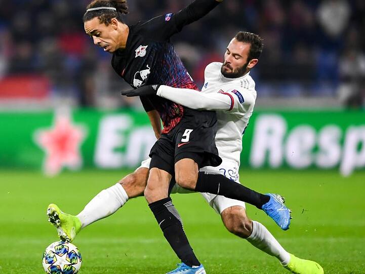 Leipzigs Yussuf Poulsen (l) wird beim Kampf um den Ball vom Lyoner Lucas Tousart gehalten.