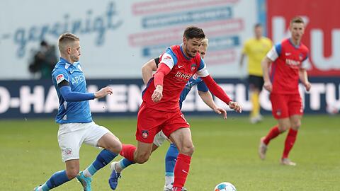 Nico Neidhart (l) und Simon Rein (r) von Hansa Rostock gegen Tim Kleindienst vom 1. FC Heidenheim.
