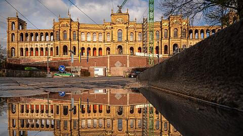 Der Bayerische Landtag spiegelt sich nach einem Regenschauer in einer Pfütze auf der Maximiliansbrücke.
