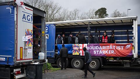 "Solidarität ist stärker" steht auf einem Banner. Die Lastwagenfahrer streiken auf einer Raststätte. Sie fordern ausstehenden Lohn von ihrem Arbeitgeber.