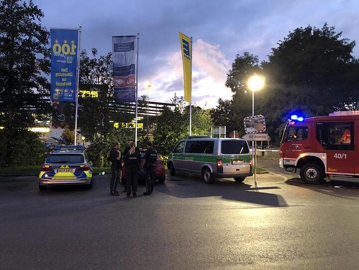 Fahrzeuge von Polizei und Feuerwehr stehen vor einem Supermarkt in dem Schüsse gefallen sind. Foto: Alexander Auer/dpa