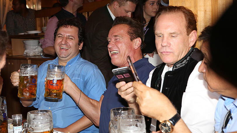 Erst eine kühle Maß, danach Dirigieren auf der Bühne: Die Bilder vom Schwarzenegger-Besuch im Schützen-Festzelt.
