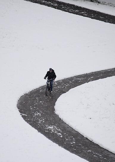 Eine Radlerin bahnt sich ihren Weg durch den verschneiten Olympiapark.