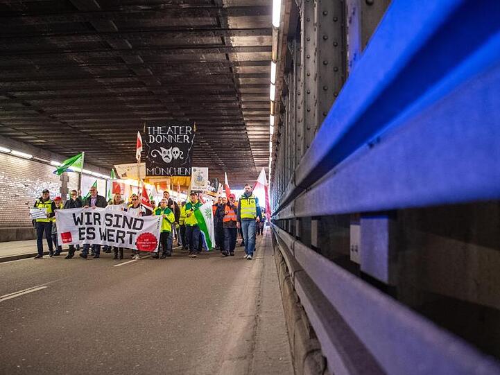 Warnstreik in Bayern: Demonstranten gehen mit Plakaten durch einen Tunnel.