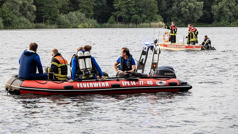 Helfer suchen mit Booten und Tauchern nach einem vermissten Schwimmer. Helfer suchen mit Booten und Tauchern nach einem vermissten Schwimmer.
