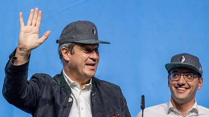 Markus Söder (links) winkt während der Landesversammlung der Jungen Union Bayern 2021 neben Christian Doleschal zu den Delegierten.