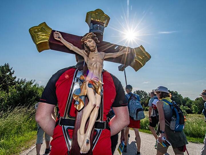 Ein Pilger trägt während der größten Fußwallfahrt Deutschlands ein Holzkreuz. Foto: Armin Weigel