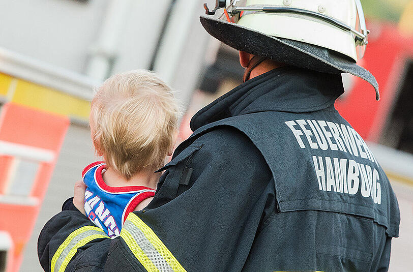 Ein Feuerwehrmann bringt ein Kind in Sicherheit. Bei dem Brand in einem ehemaligen Bunker sind zahlreiche Menschen verletzt worden.