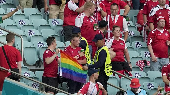 Ordner nehmen zwei Dänemark Fans eine Regenbogen-Fahne ab.