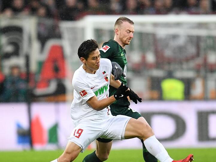 Maximilian Arnold (r.) von Wolfsburg und Ja-Cheol Koo von Augsburg kämpfen um den Ball. Foto: Tobias Hase