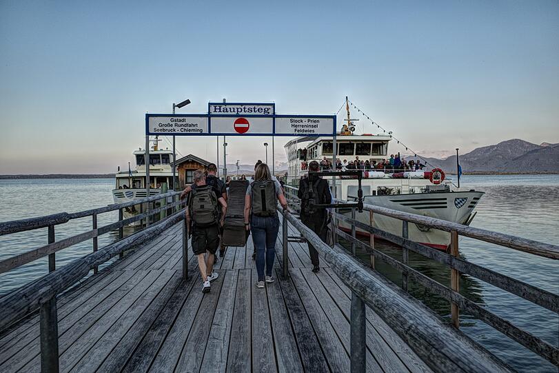 Nach dem Konzert auf Frauenchiemsee wird das Cembalo an Bord der &bdquo;Edeltraud&ldquo; (rechts) gebracht. Das Schiff bringt auch die Konzertbesucher in der Abenddämmerung zurück zu den Parkplätzen am Hafen von Prien-Stock.