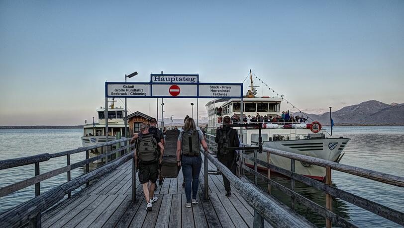 Nach dem Konzert auf Frauenchiemsee wird das Cembalo an Bord der &bdquo;Edeltraud&ldquo; (rechts) gebracht. Das Schiff bringt auch die Konzertbesucher in der Abenddämmerung zurück zu den Parkplätzen am Hafen von Prien-Stock.