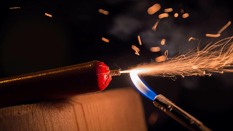 Ein Silvesterböller wird mit einem Feuerzeug gezündet.