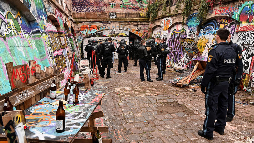 Polizeibeamte stehen in den frühen Morgenstunden auf einem mit unzähligen Flaschen und Spraydosen übersäten Bereich am Schlachthof.
