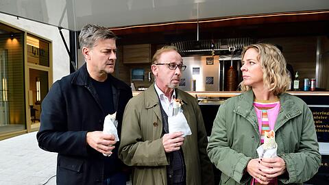 Harald Neuhauser (l, Marcus Mittermeier), Ludwig Schaller (Alexander Held) und Angelika Flierl (Bernadette Heerwagen) stehen vor einem Imbissstand.