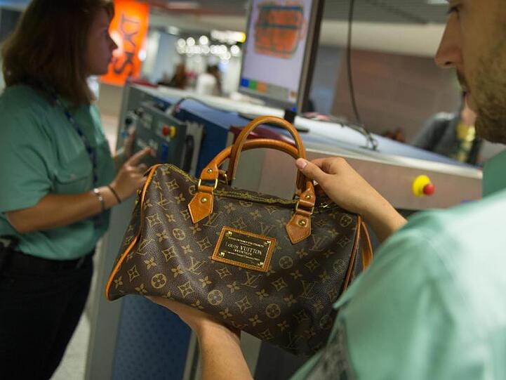 Flughafen Düsseldorf: Ein Zollbeamter hält eine gefälschte Louis-Vuitton-Handtasche in der Hand.