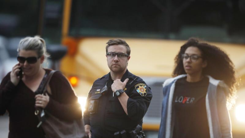 Ein Polizist schützt nach der Bluttat Schüler, die vor der angegriffenen Highschool aus einem Bus steigen. Ein Polizist schützt nach der Bluttat Schüler, die vor der angegriffenen Highschool aus einem Bus steigen.