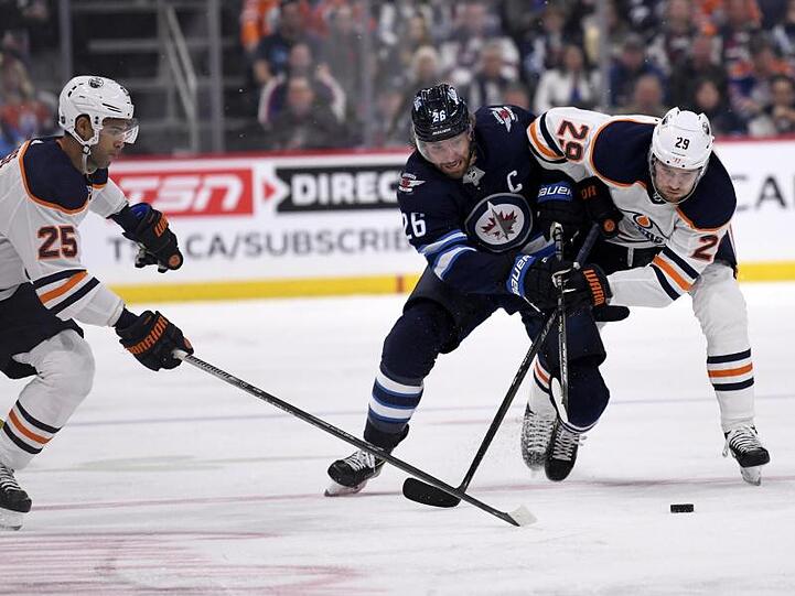Blake Wheeler (M.) von den Winnipeg Jets im Zweikampf mit Leon Draisaitl (r).