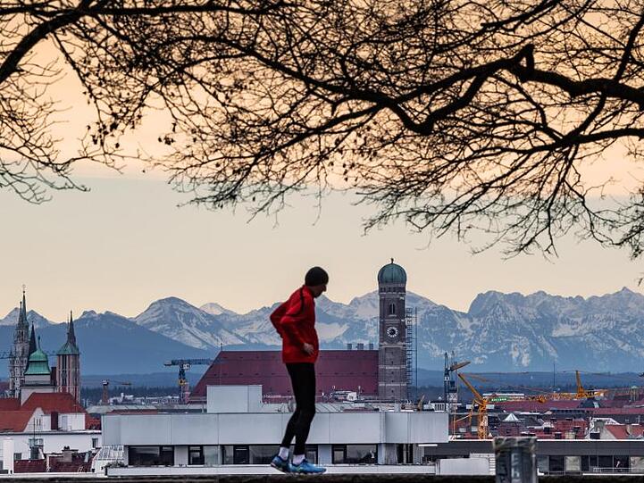 Der Winter zieht sich in die Berge zurück: Hinter der Skyline von München ist das leicht verschneite Alpenpanorama zu erkennen.