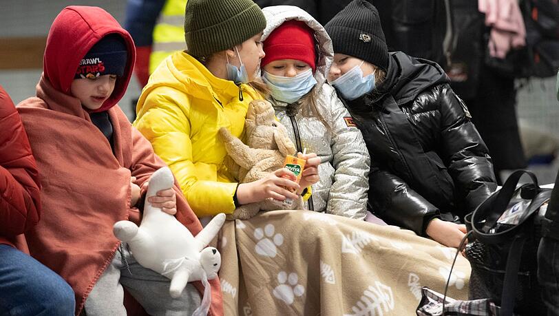 In Decken gehüllt sitzen diese Kinder aus dem ukrainischen Kriegsgebiet auf einer Bank im Berliner Hauptbahnhof.