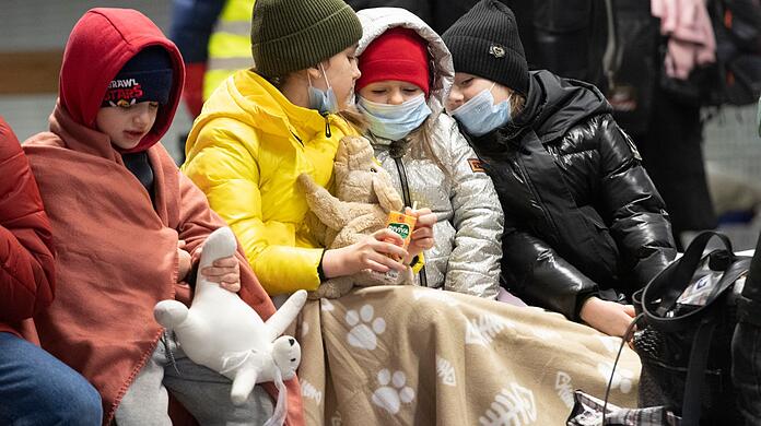 In Decken gehüllt sitzen diese Kinder aus dem ukrainischen Kriegsgebiet auf einer Bank im Berliner Hauptbahnhof.