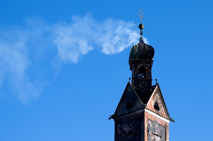 Rauch steigt aus dem beschädigten Turm des historischen Gebäudes auf.