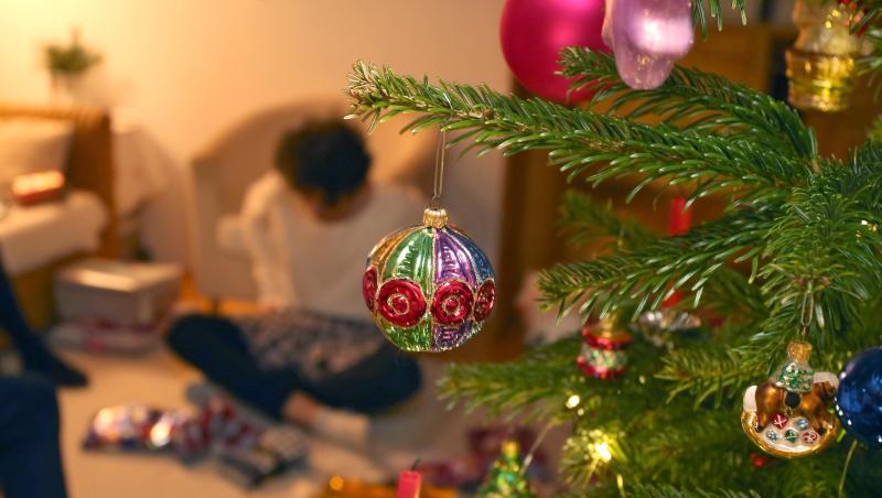 Eine Junge packt hinter einem geschmücktem Christbaum Weihnachtsgeschenke aus. Eine Junge packt hinter einem geschmücktem Christbaum Weihnachtsgeschenke aus.