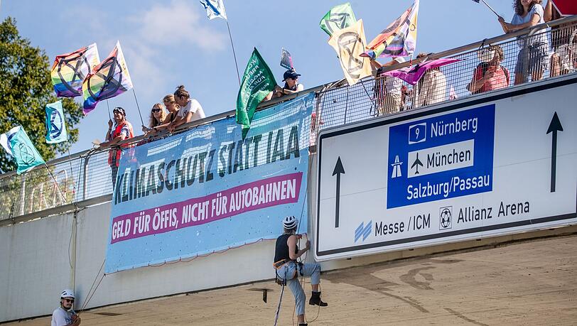 IAA-Gegner seilen sich über einer Straße in München ab.