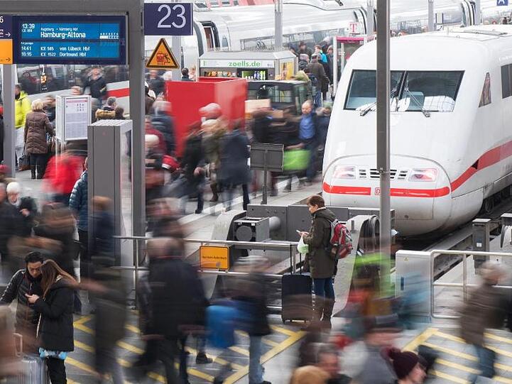 Reisende gehen am Münchner Hauptbahnhof über eine Plattform.