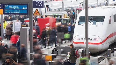 Reisende gehen am Münchner Hauptbahnhof über eine Plattform.