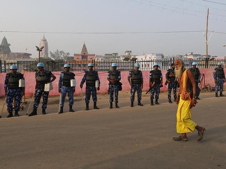 Ein Sadhu - ein hinduistischer Heiliger - geht in Ayodhya an Sicherheitsoffizieren vorbei. Der Streit zwischen Hindus und Muslimen um ein heiliges Areal hatte 1992 zu Ausschreitungen mit mehr als 2000 Toten geführt.