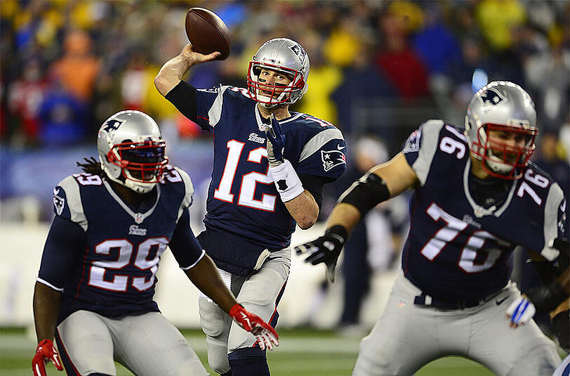 Vollmer (r.) beschützt seinen Quarterback Tom Brady (m.).