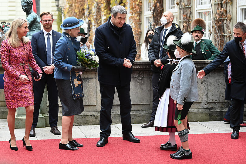 Ein Bub in Tracht plaudert mit Markus Söder und Königin Margrethe