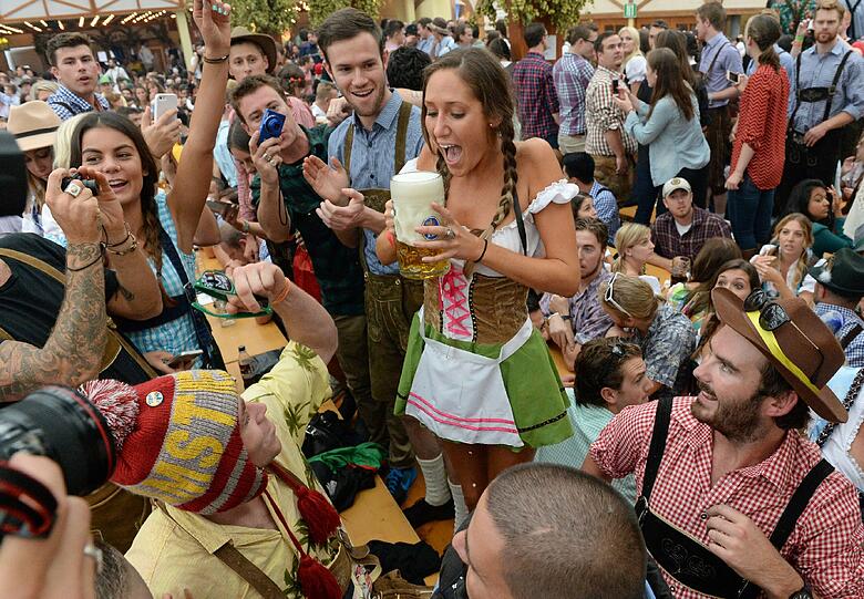 Eine junge Frau in einem recht kanppen Dirndl freut sich im Hofbräuzelt über eine Maß Bier, die kostenlos verteilt wurde.