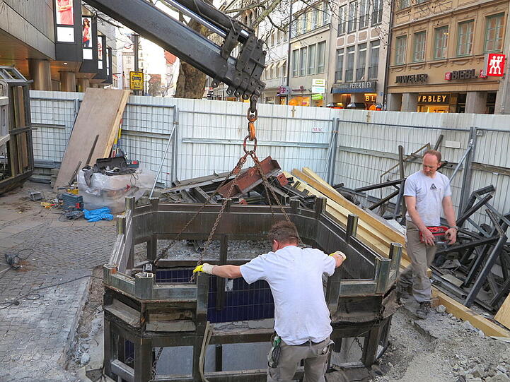 Mit dem Kran heben die Bauarbeiter den alten Aufzug zwischen Sperrengeschoss und Oberfläche am Marienplatz aus den Fugen.