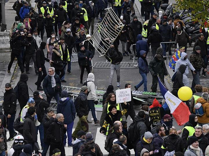 Demonstranten haben in Paris Absperrgitter umgestoßen.