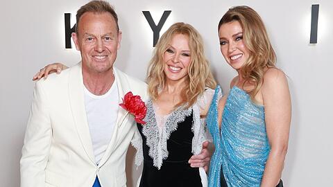 Kylie Minogue (M.) mit Ex-Freund Jason Donovan und Schwester Dannii posieren bei der Doku-Premiere in London.