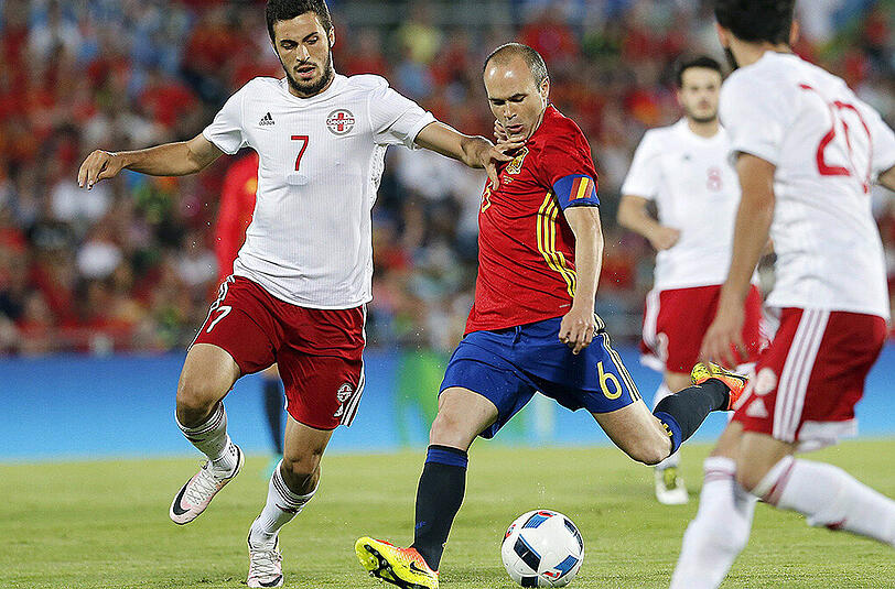 Spaniens Kapitän Andres Iniesta (Mitte) wird vom Georgier Giorgi Aburjania (links) attackiert.