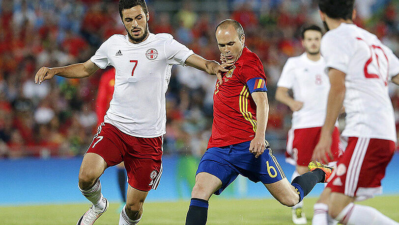 Spaniens Kapitän Andres Iniesta (Mitte) wird vom Georgier Giorgi Aburjania (links) attackiert. Spaniens Kapitän Andres Iniesta (Mitte) wird vom Georgier Giorgi Aburjania (links) attackiert.