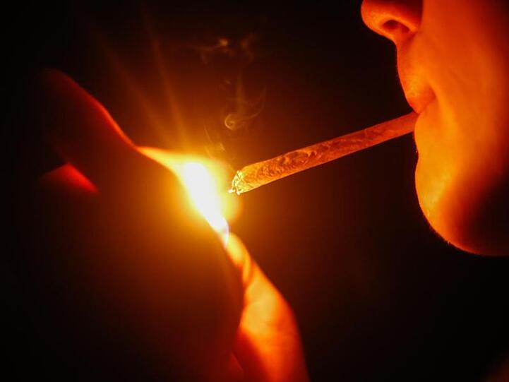 Ein junger Mann zündet sich einen Joint an.