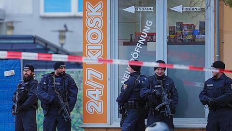 Mit Maschinenpistolen bewaffnete Einsatzkräfte der Polizei vor einem Kiosk am Tatort in Hanau-Kesselstadt.