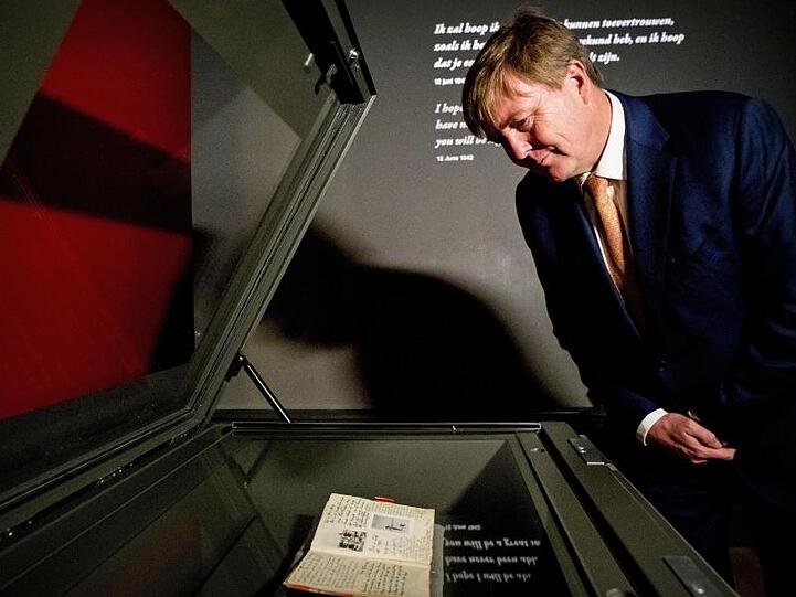 König Willem-Alexander der Niederlande betrachtet das Tagebuch der Anne Frank in einer Vitrine.