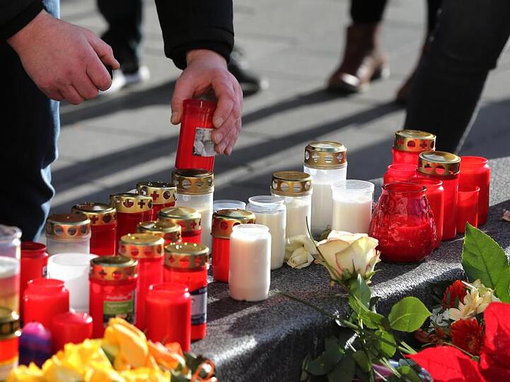Ein Mann plaziert ein Grablicht an einem Rondell am Königsplatz. Foto: Karl-Josef Hildenbrand/dpa