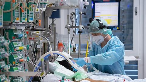 Ein Intensivpfleger kümmert sich um einen Patienten.