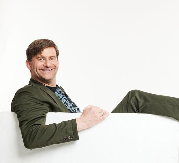 Michael Altinger fläzt am Tisch.